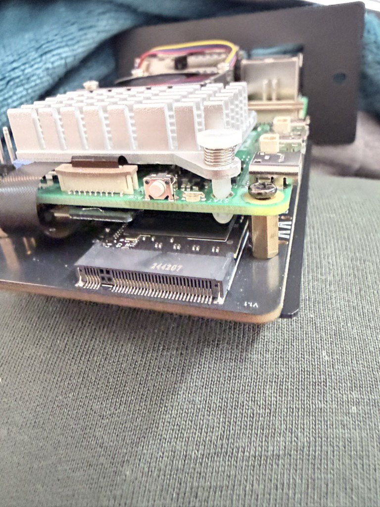 Close-up of Raspberry Pi with SATA adapter and custom homelab frame.